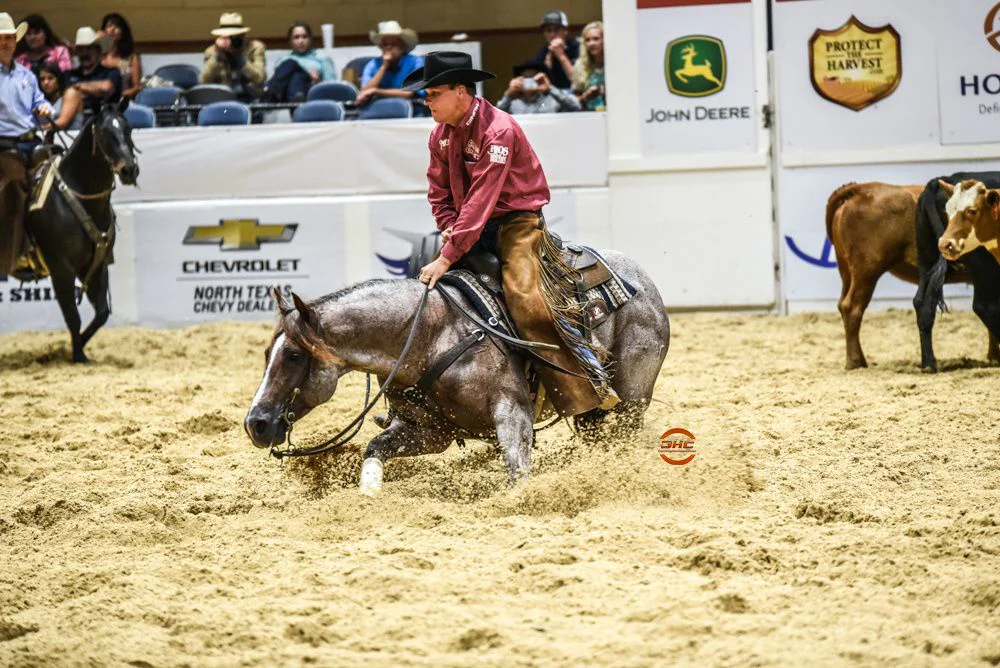 A cowboy in a hat rides a stevie rey von in an indoor arena during a cutting horse competition